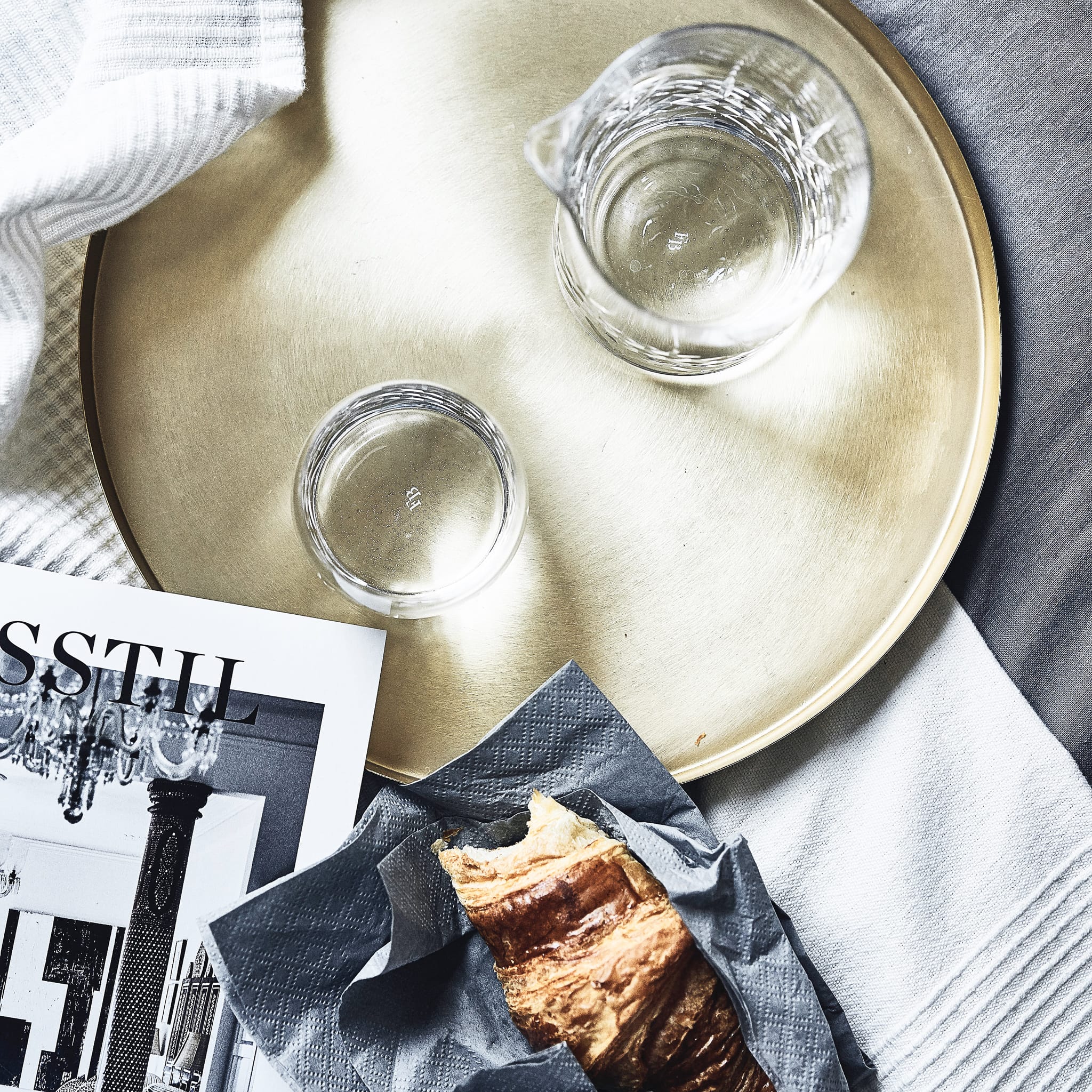 Skandinavisk bord med klart krystallglass fra Frederik Bagger og croissant på mørkt serviett
