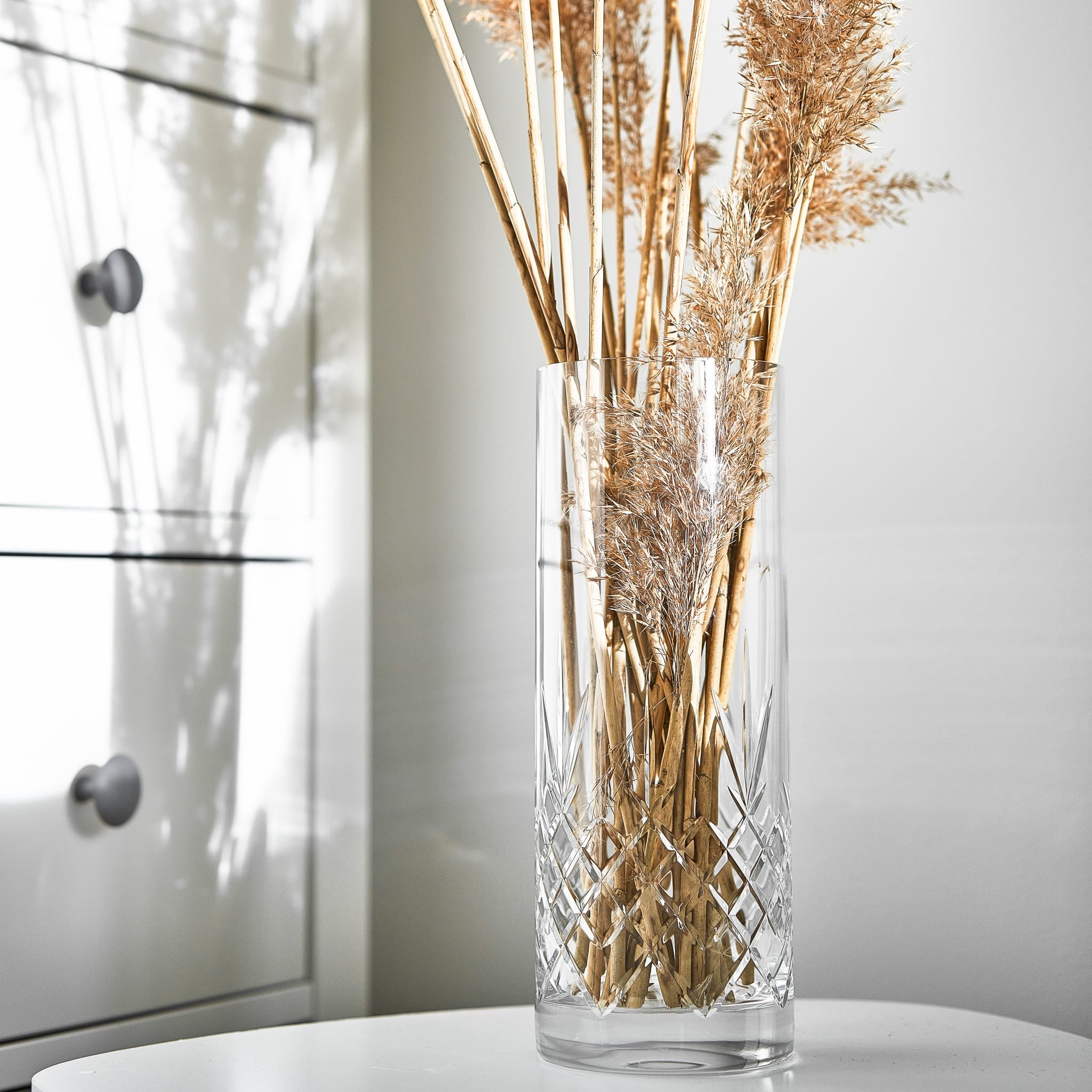 Skandinavisk klar glassvase med diamantmønster fra Frederik Bagger, dekorert med tørkede strå i minimalistisk interiør.